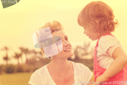 Image of mother and little daughter playing at backyard