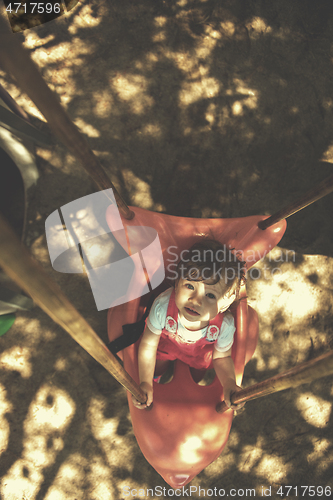 Image of little girl swinging  on a playground