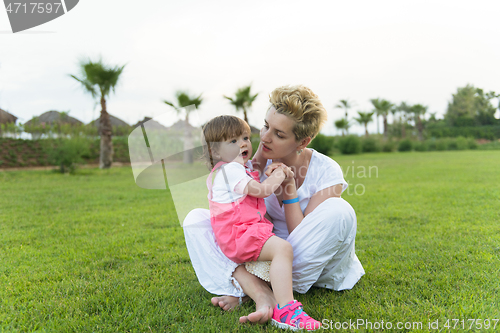 Image of mother and little daughter playing at backyard