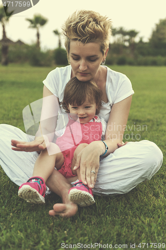 Image of mother and little daughter playing at backyard