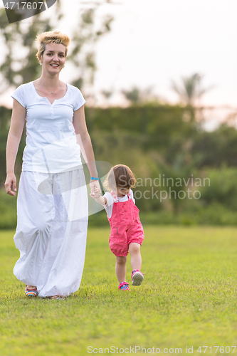 Image of mother and little daughter playing at backyard