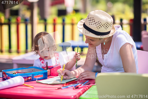 Image of mom and little daughter drawing a colorful pictures