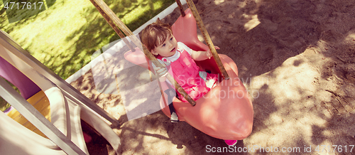 Image of little girl swinging  on a playground