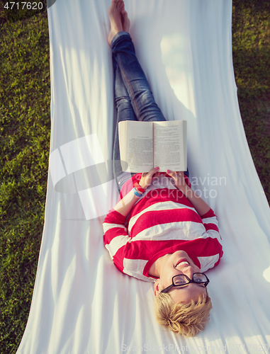 Image of woman reading a book while relaxing on hammock