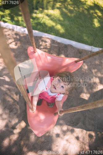 Image of little girl swinging  on a playground