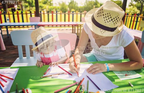 Image of mom and little daughter drawing a colorful pictures