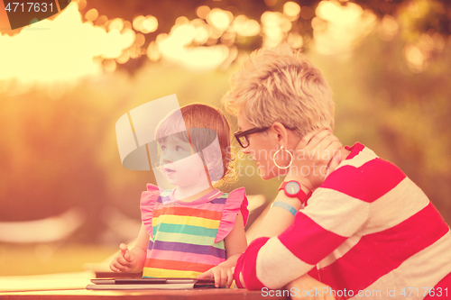 Image of mom and her little daughter using tablet computer