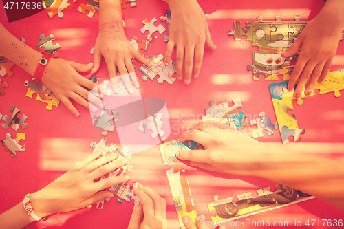 Image of top view of kids hands playing with puzzles