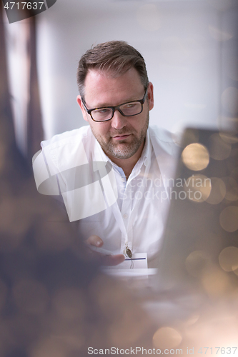 Image of Business man writing notes while working on laptop