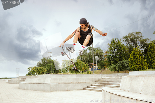 Image of Skateboarder doing a trick at the city\'s street in cloudly day