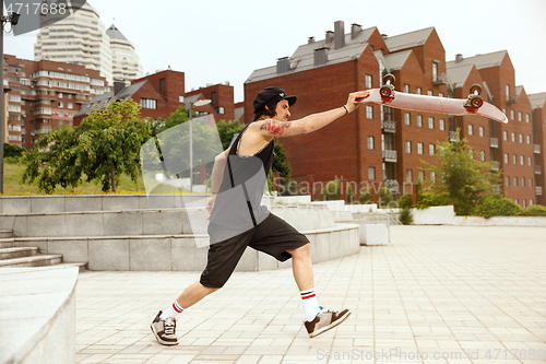 Image of Skateboarder doing a trick at the city\'s street in cloudly day