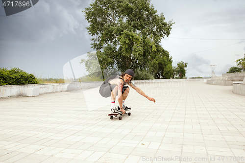 Image of Skateboarder doing a trick at the city\'s street in cloudly day