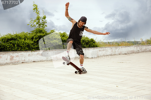 Image of Skateboarder doing a trick at the city\'s street in cloudly day