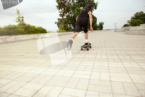 Image of Skateboarder doing a trick at the city\'s street in cloudly day