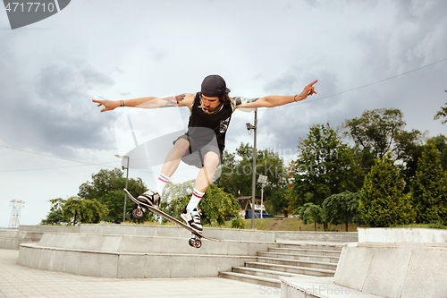 Image of Skateboarder doing a trick at the city\'s street in cloudly day