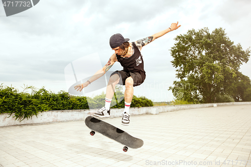 Image of Skateboarder doing a trick at the city\'s street in cloudly day