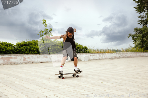 Image of Skateboarder doing a trick at the city\'s street in cloudly day