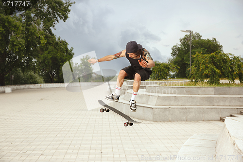 Image of Skateboarder doing a trick at the city\'s street in cloudly day