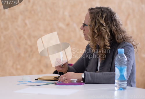 Image of Business woman writing notes while working