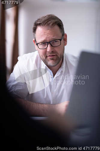 Image of Business man writing notes while working on laptop