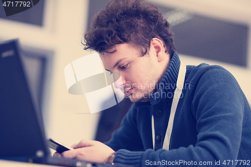 Image of Young casual businessman using smartphone