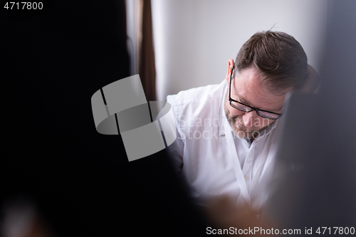 Image of Business man writing notes while working on laptop