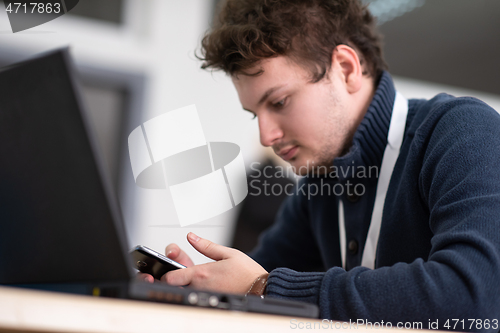 Image of Young casual businessman using smartphone