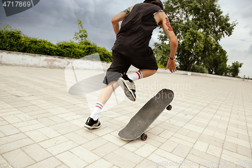 Image of Skateboarder doing a trick at the city\'s street in cloudly day