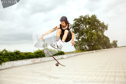 Image of Skateboarder doing a trick at the city\'s street in cloudly day