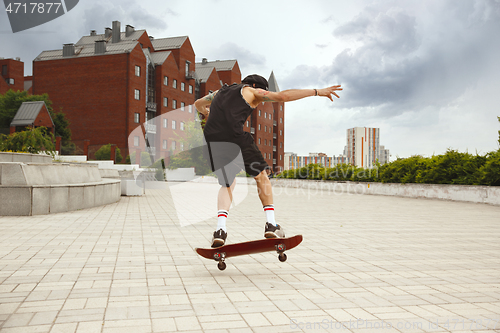 Image of Skateboarder doing a trick at the city\'s street in cloudly day