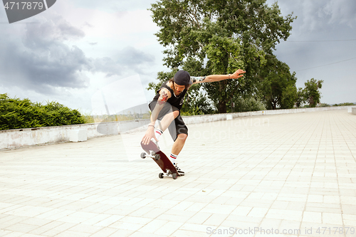 Image of Skateboarder doing a trick at the city\'s street in cloudly day