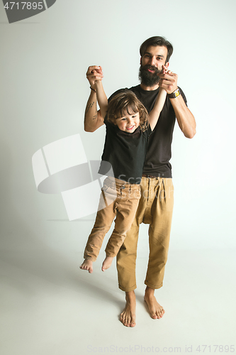 Image of Father playing with young son against white studio background