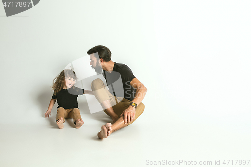 Image of Father playing with young son against white studio background