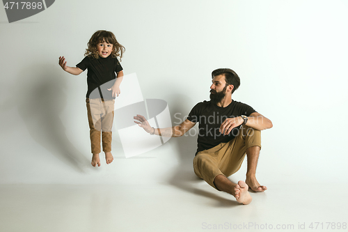 Image of Father playing with young son against white studio background