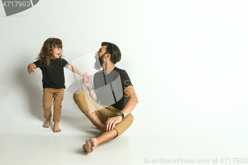Image of Father playing with young son against white studio background