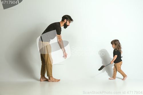 Image of Father playing with young son against white studio background