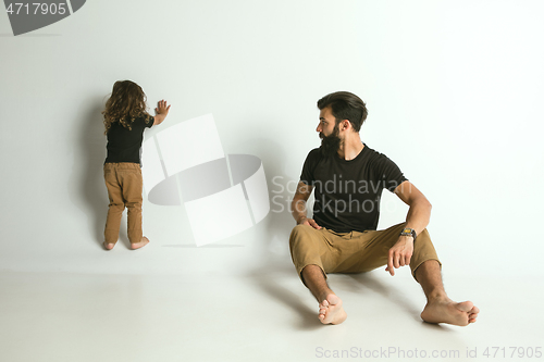 Image of Father playing with young son against white studio background