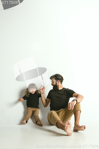 Image of Father playing with young son against white studio background