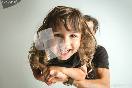 Image of Father playing with young son against white studio background