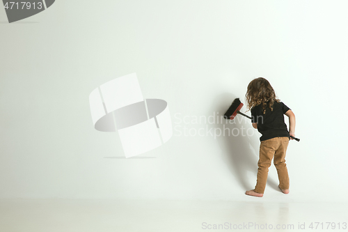 Image of Little child sitting and playing in armchair on white studio background