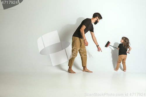 Image of Father playing with young son against white studio background