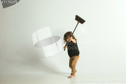 Image of Little child sitting and playing in armchair on white studio background