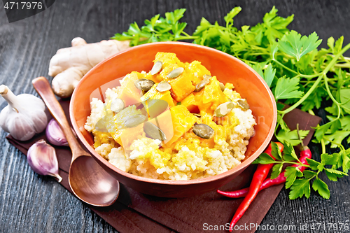 Image of Porridge millet with spicy pumpkin in clay bowl on wooden board