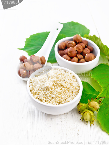 Image of Flour and hazelnuts in bowls on light wooden board