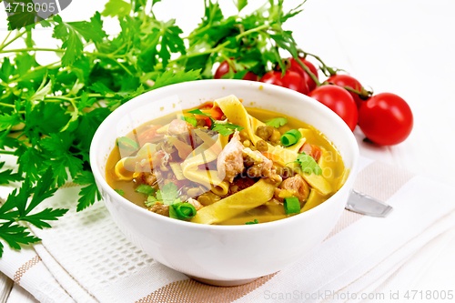 Image of Soup with mung and noodles in bowl on wooden board