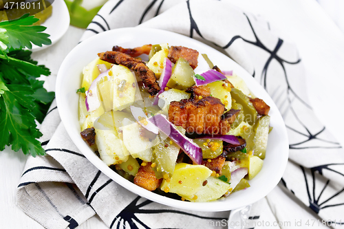 Image of Salad potato with bacon and cucumber in plate on napkin