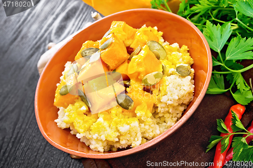 Image of Porridge millet with spicy pumpkin in clay bowl on board