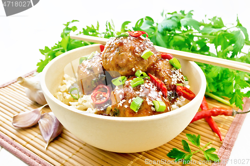 Image of Meatballs in sweet and sour sauce with rice on light wooden boar