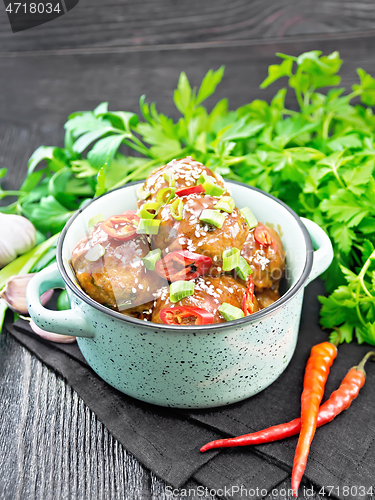 Image of Meatballs in sweet and sour sauce on wooden board