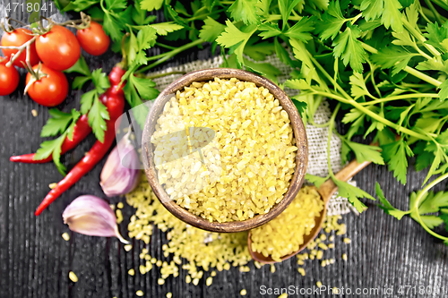 Image of Bulgur in bowl with vegetables on dark board top